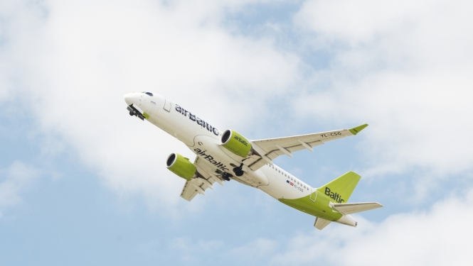 airbaltic lidmašīna pacēlusies gaisā dienas laikā, fonā daži mākoņi