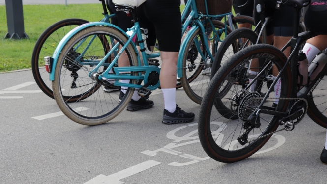 Trīs velosipēdi stāv uz ar velo zīmi apzīmēta veloceļa