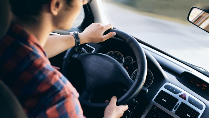 vīrietis rūtainā kreklā pie vieglā auto stūres
