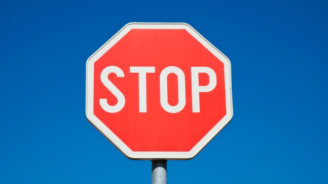 Ceļa zīme “STOP” uz zilu debesu fona