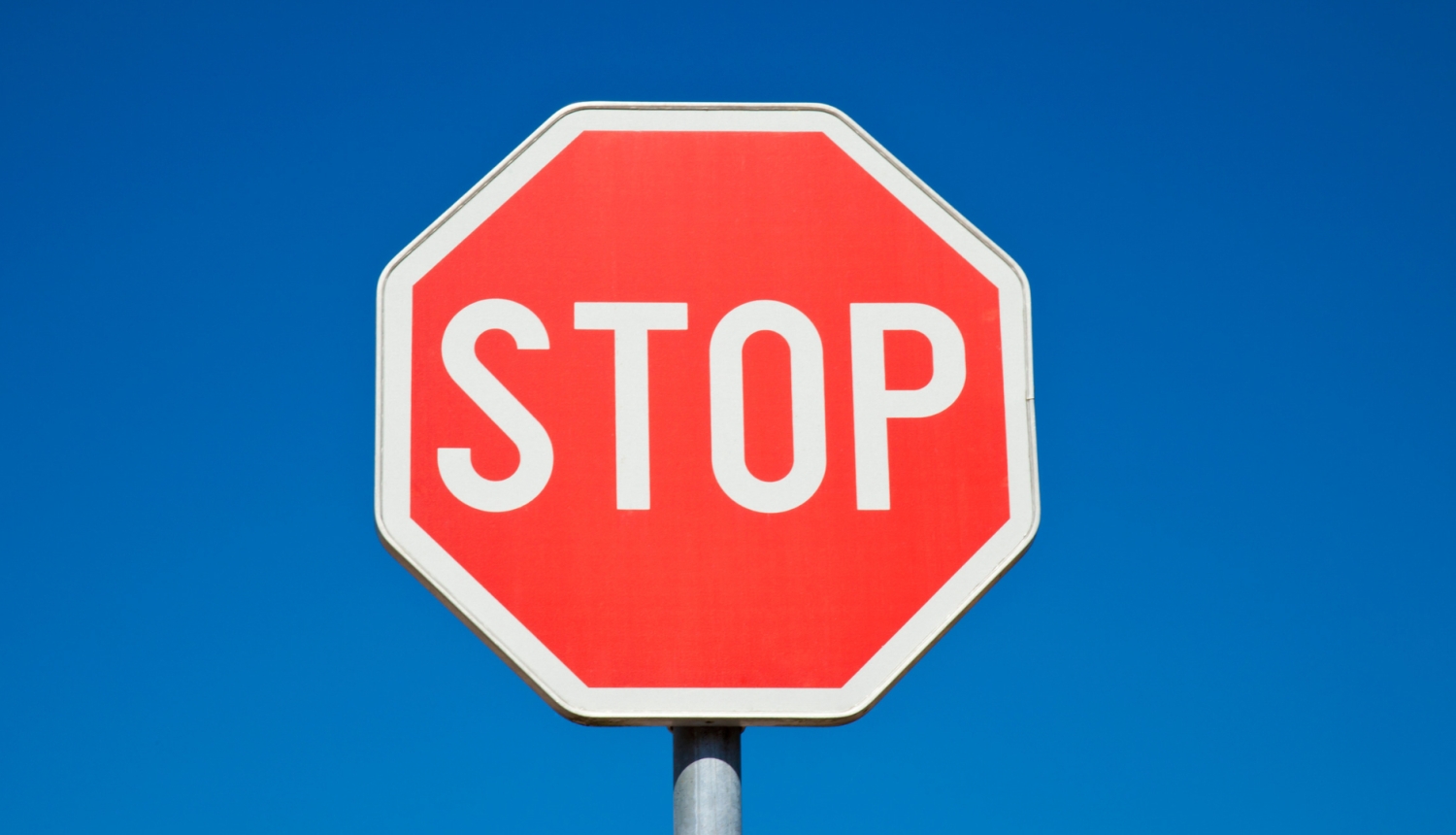 Ceļa zīme “STOP” uz zilu debesu fona