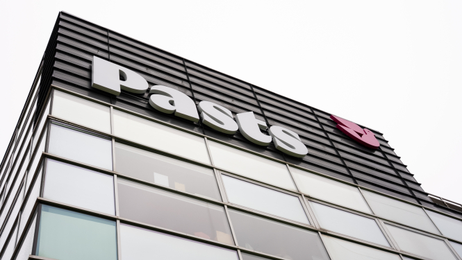 Nofotografēta Pasta ēkas daļa. Redzama logu siena un uz tās PASTS logo.