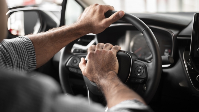 vīrieša rokas uz auto stūres