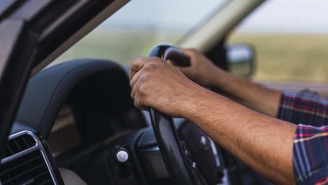 vīrieša rokas uz auto stūres