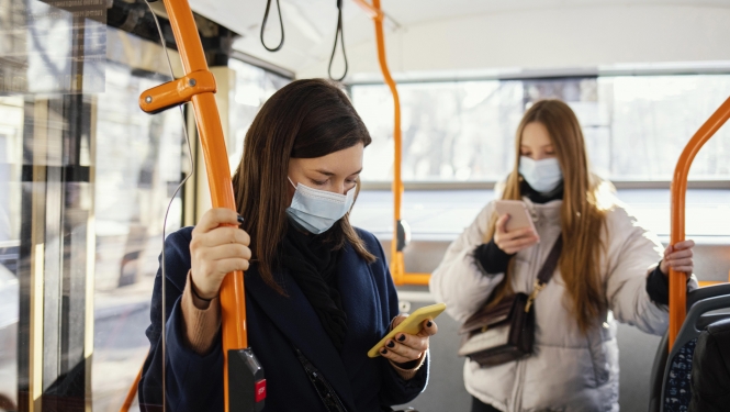 divas sievietes sabiedriskajā transportā skatās savos telefonos
