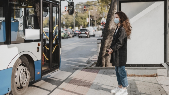 sieviete gaida sabiedrisko transportu pieturā