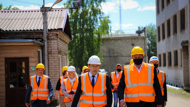 cilvēki oranžās vestēs un baltās ķiverēs