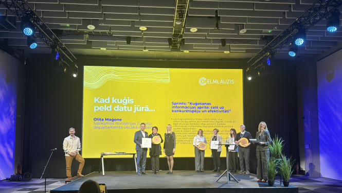 Satiksmes ministrijas pārstāvji saņem balvu uz pasākuma skatuves