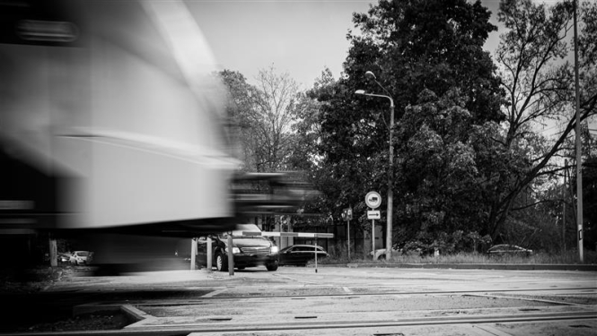 Dzelzceļa pārbrauktuve. Vilciens brauc, automašīnas stāv.