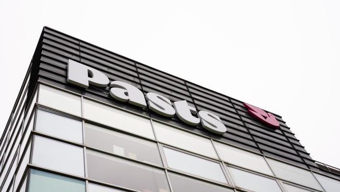 Nofotografēta Pasta ēkas daļa. Redzama logu siena un uz tās PASTS logo.