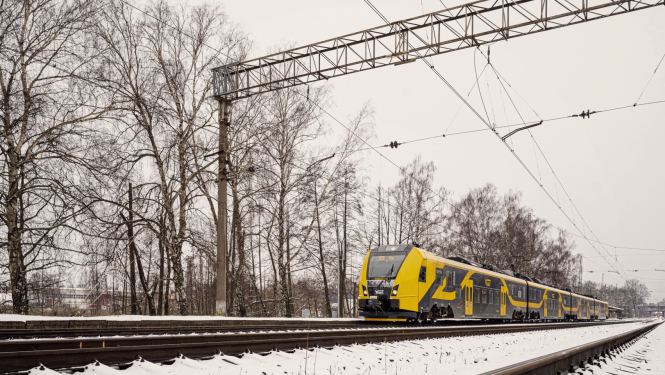 Vivi vilciens uz sliedēm ziemā. Uz zemes uzsnidzis sniegs