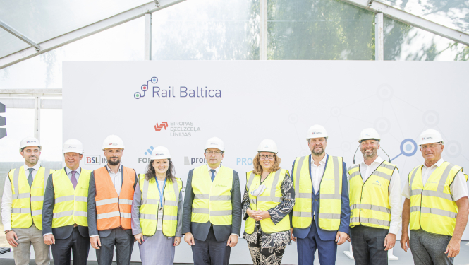 cilvēki ķiverēs un dzeltenās vestēs