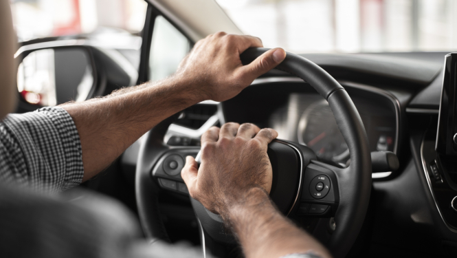 vīrieša rokas uz auto stūres