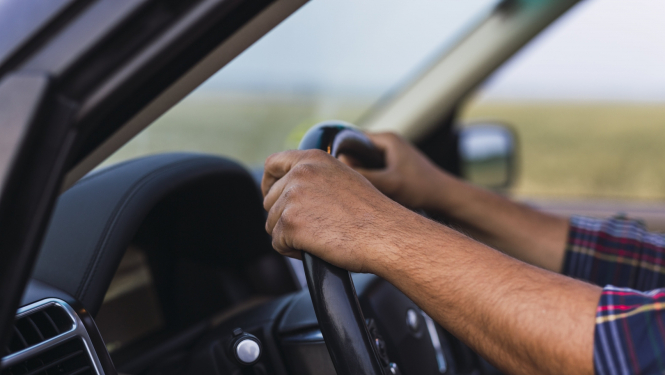 vīrieša rokas uz auto stūres