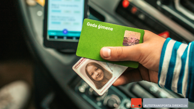 Cilvēka roka tur ID karti un Goda ģimenes karti