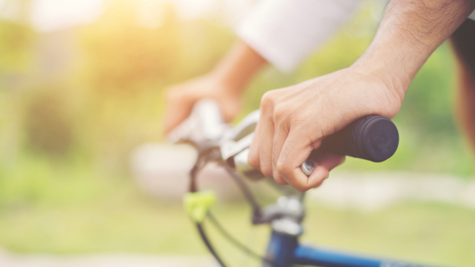 sievietes rokas uz velosipēda stūres