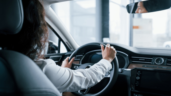 skats uz sievieti pie auto stūres no mugurpuses