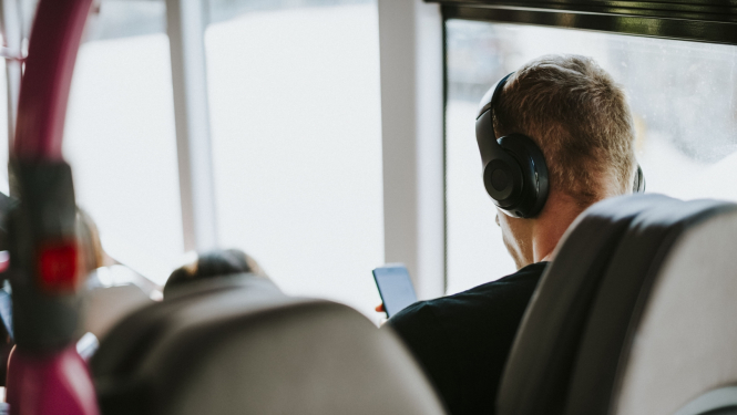Vīrietis sabiedriskajā transportā klausās mūziku austiņās