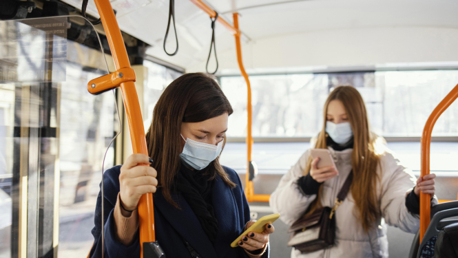 divas sievietes sabiedriskajā transportā skatās savos telefonos