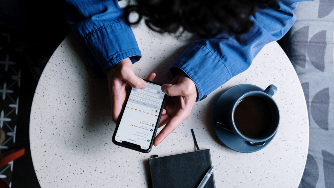 sievietes pie kafijas galdiņa ar viedtālruni rokās