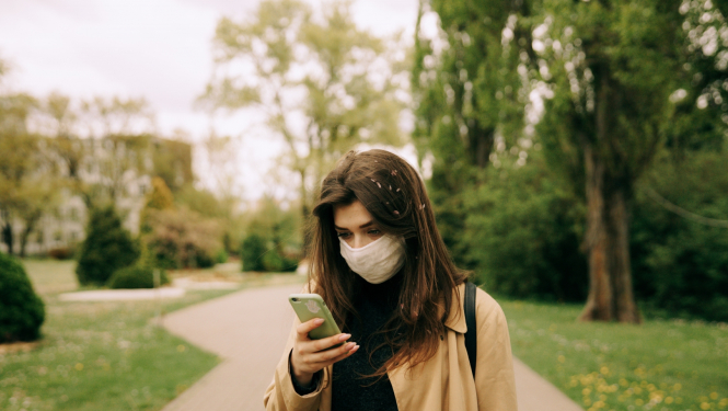 sieviete parkā lūkojas uz viedtālruni