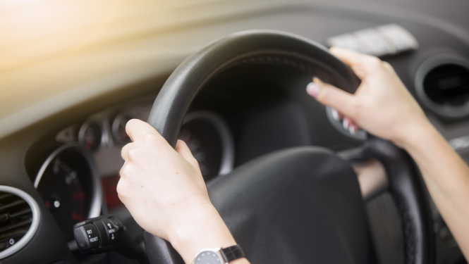 sievietes rokas uz automašīnas stūres