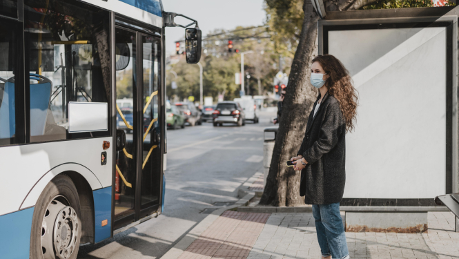sieviete gaida sabiedrisko transportu pieturā