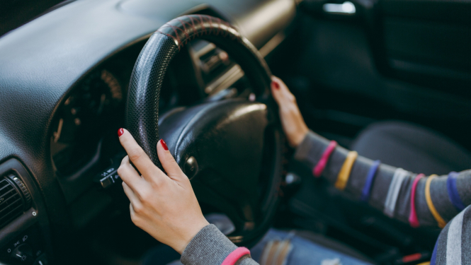 sievietes rokas uz stūres