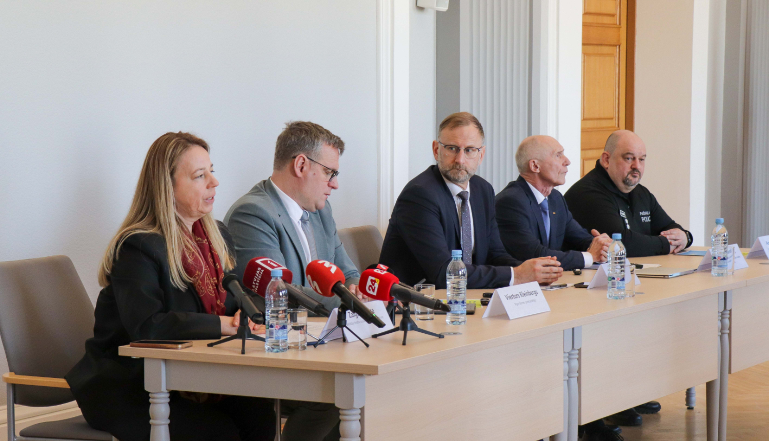 Preses konferences pieci dalībnieki sēž pie galdiem uz kuriem ir mediju mikrofoni