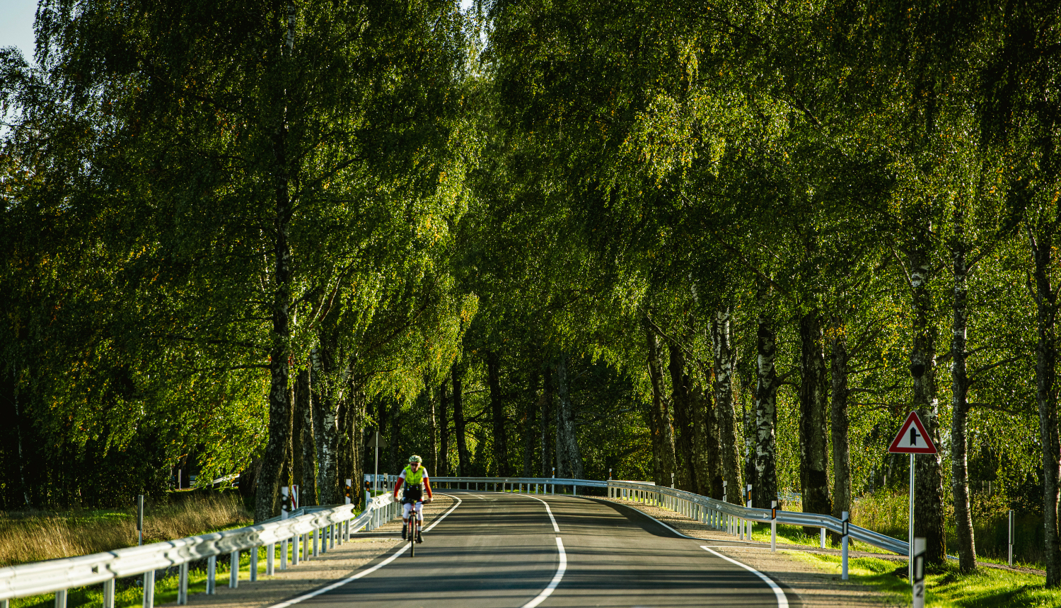 velosipēdists uz autoceļa vasaras dienā