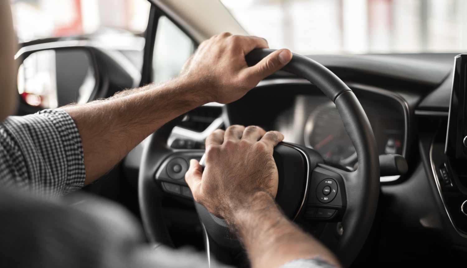 vīrieša rokas uz auto stūres
