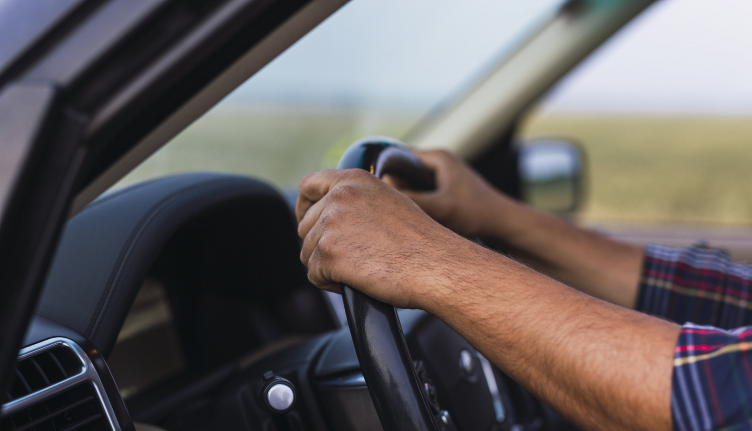 vīrieša rokas uz auto stūres