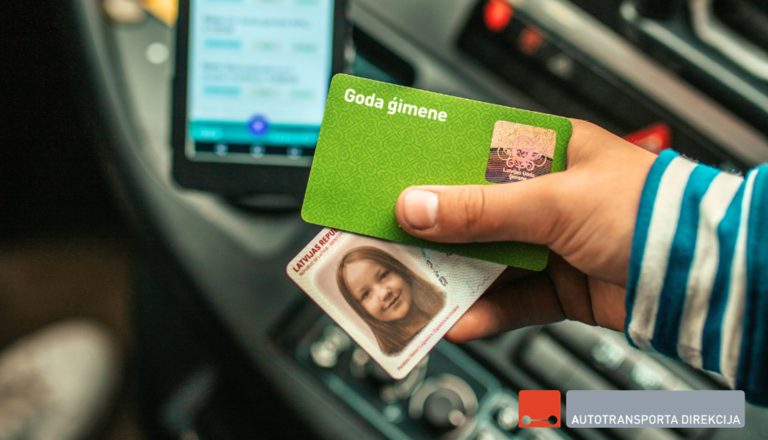 Cilvēka roka tur ID karti un Goda ģimenes karti