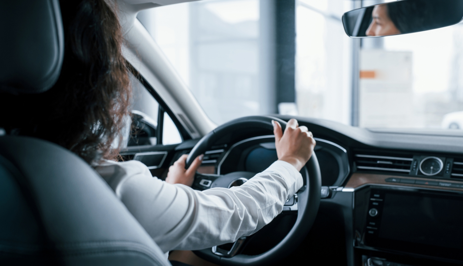 skats uz sievieti pie auto stūres no mugurpuses