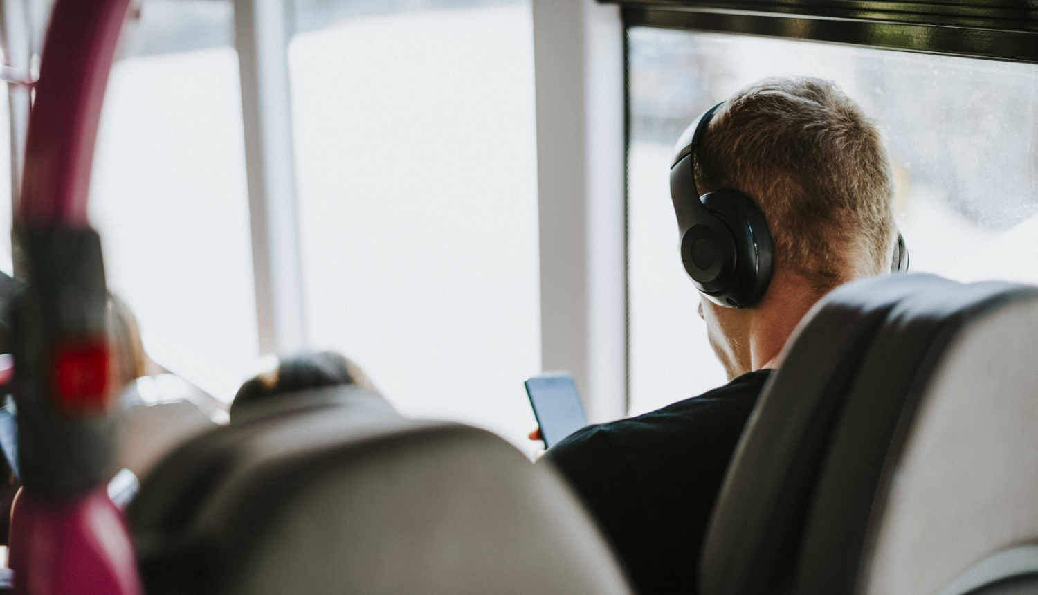 Vīrietis sabiedriskajā transportā klausās mūziku austiņās