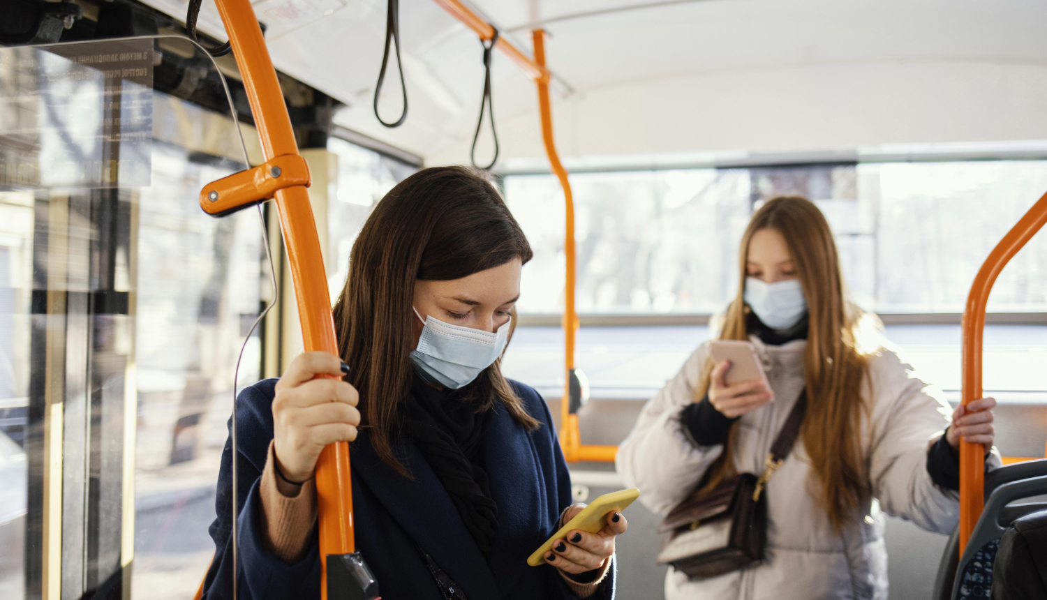 divas sievietes sabiedriskajā transportā skatās savos telefonos