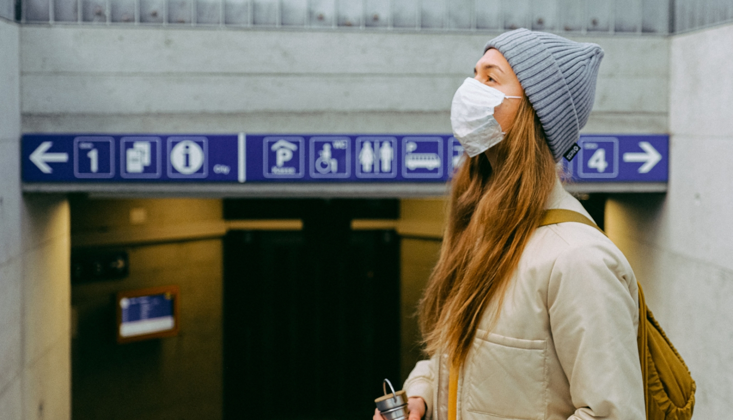 jauna sieviete sejas maskā stacijā