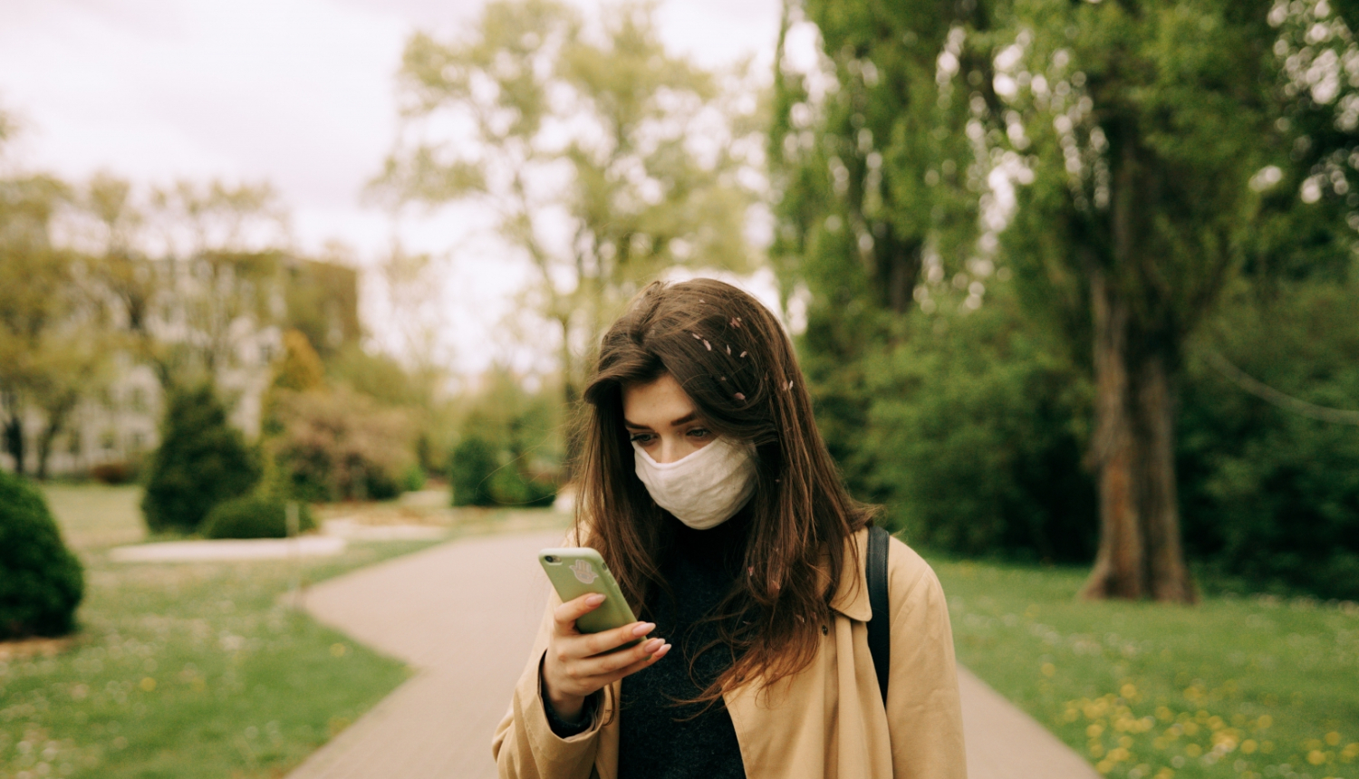 sieviete parkā lūkojas uz viedtālruni