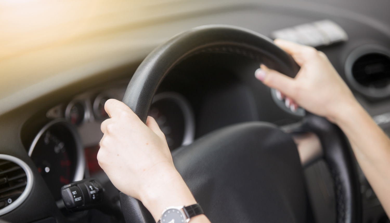 sievietes rokas uz automašīnas stūres