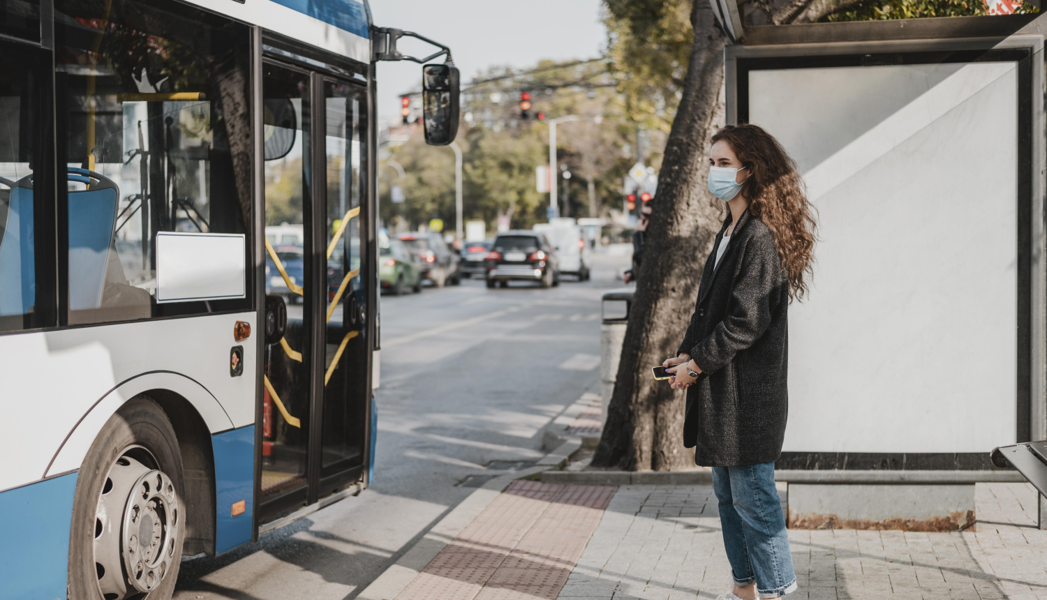sieviete gaida sabiedrisko transportu pieturā