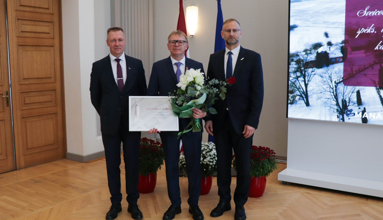 ministrs Atis Švinka un valsts sekretārs Andulis Židkovs sveic Ģirtu Ozolu