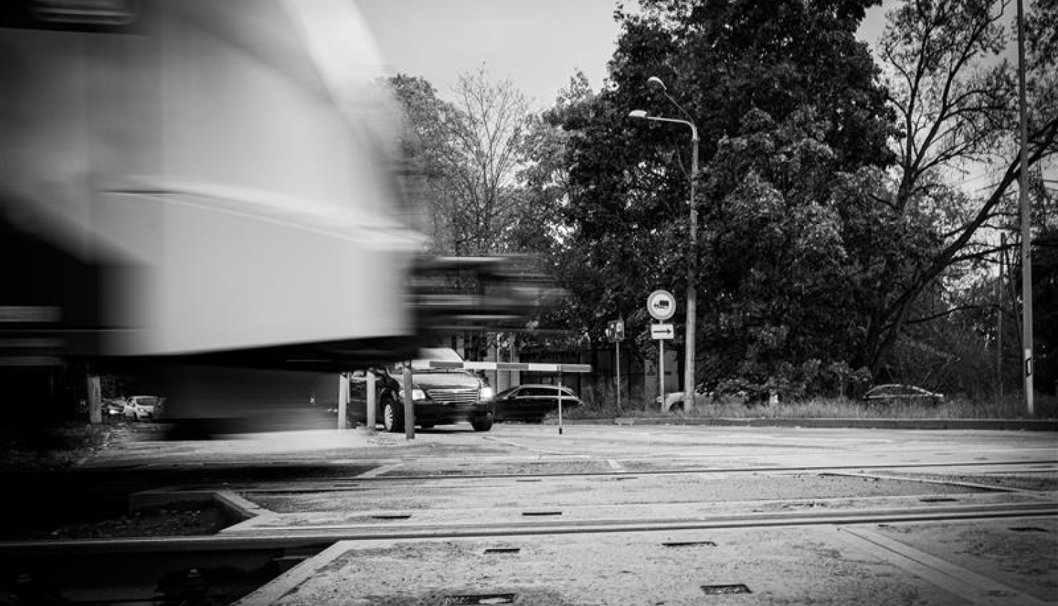 Dzelzceļa pārbrauktuve. Vilciens brauc, automašīnas stāv.