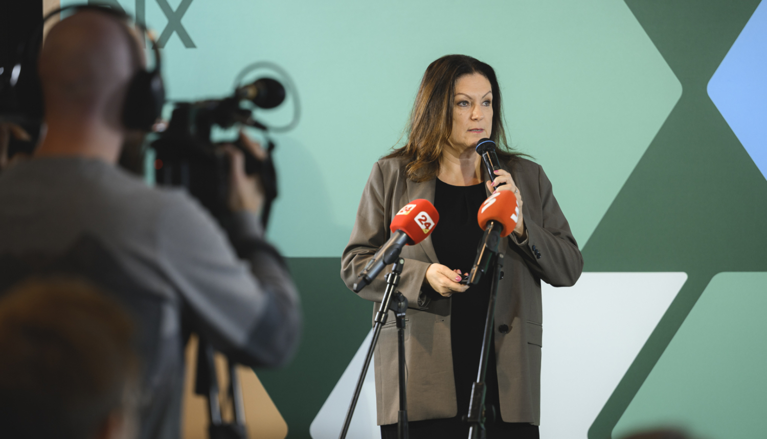 RIX Rīgas lidosta telpās tiek prezentāts plāns, prezentētāja stāv pie mediju mikrofoniem