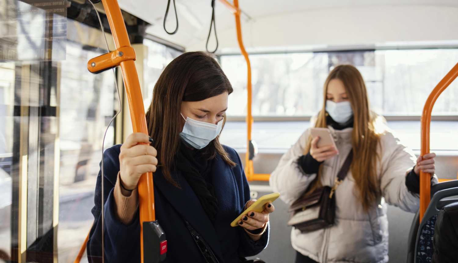 divas sievietes sabiedriskajā transportā skatās savos telefonos