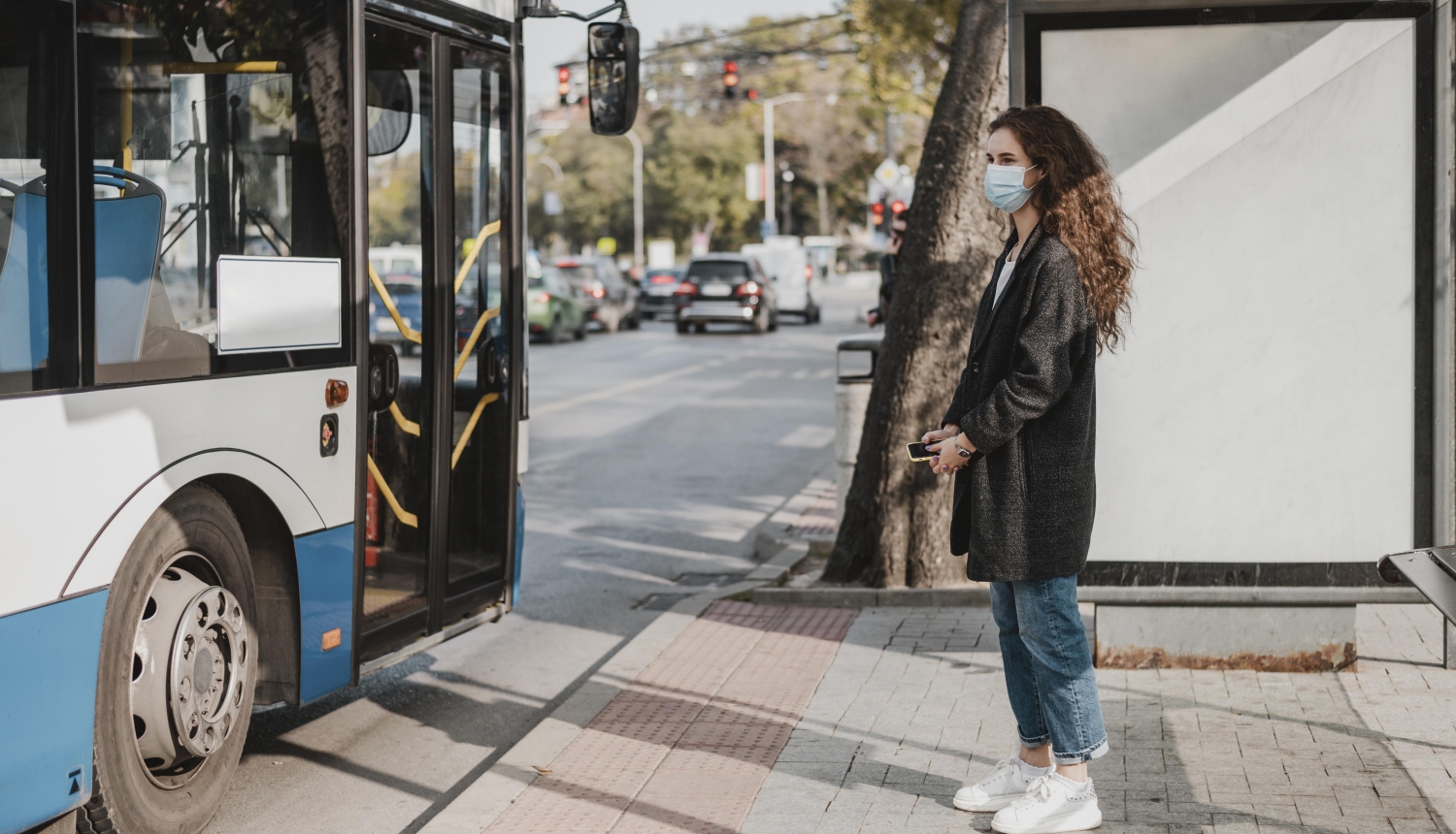 sieviete gaida sabiedrisko transportu pieturā